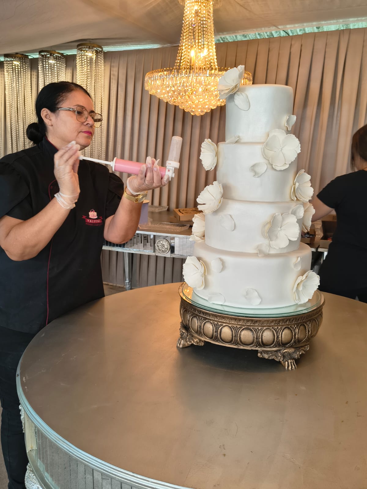 Confeiteira do Valsoni Lima Buffet finalizando um bolo de casamento de quatro andares