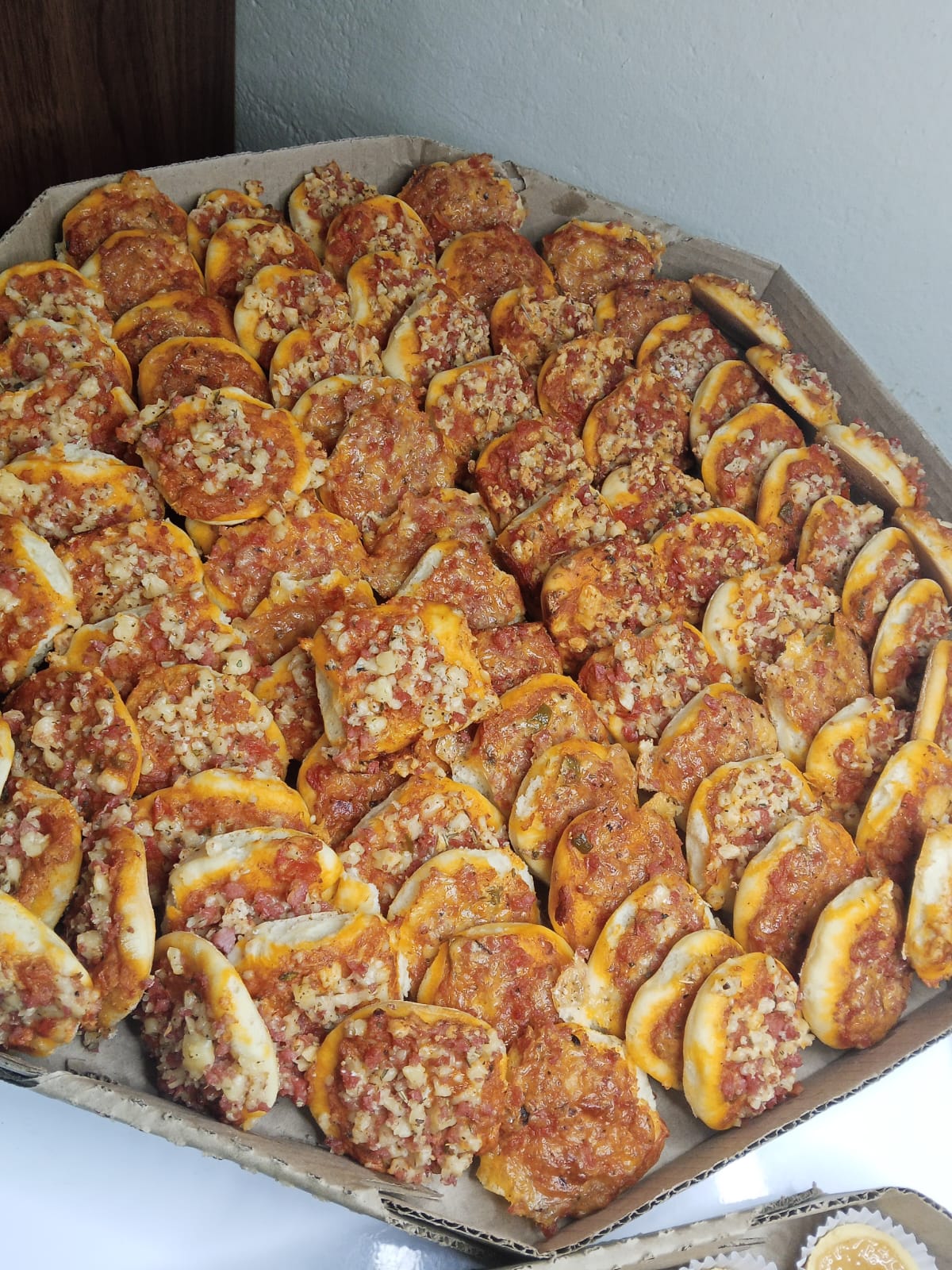 Caixa com mini pizzas de calabresa recém-assadas